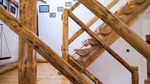Eine Holztreppe mit einzigartigem Design, die zu einem Raum mit weißer Wand und gerahmten Bildern führt.
