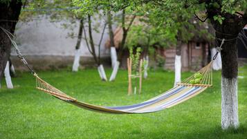 A hammock tied between two trees in a grassy area with a small green frog toy on it.