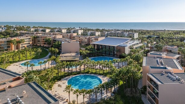 Ein Resort mit mehreren Swimmingpools, Palmen und Blick auf den Ozean.