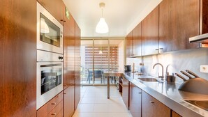 Eine moderne Küche mit Holzausstattung, Edelstahlgeräten und einem großen Fenster mit Blick auf einen Balkon.