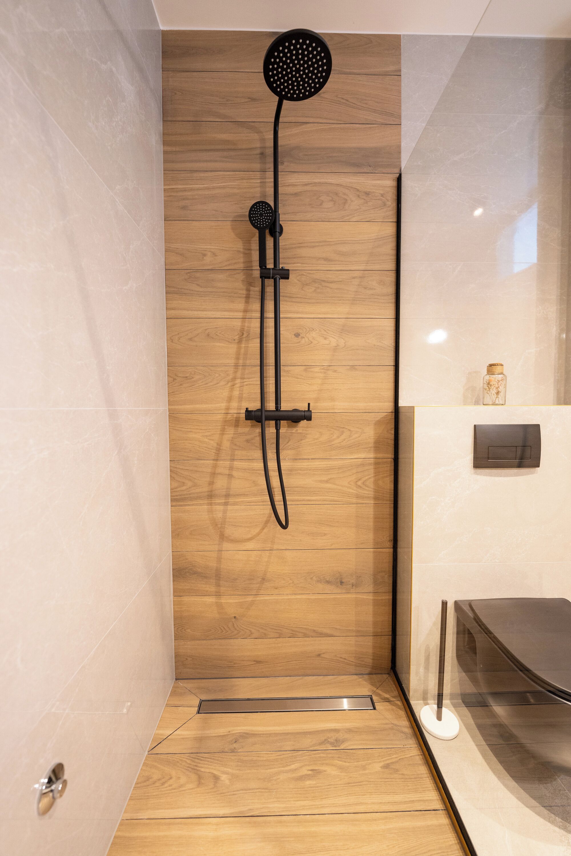 A modern shower with a wooden panel wall, a handheld showerhead, and a wall-mounted control panel.
