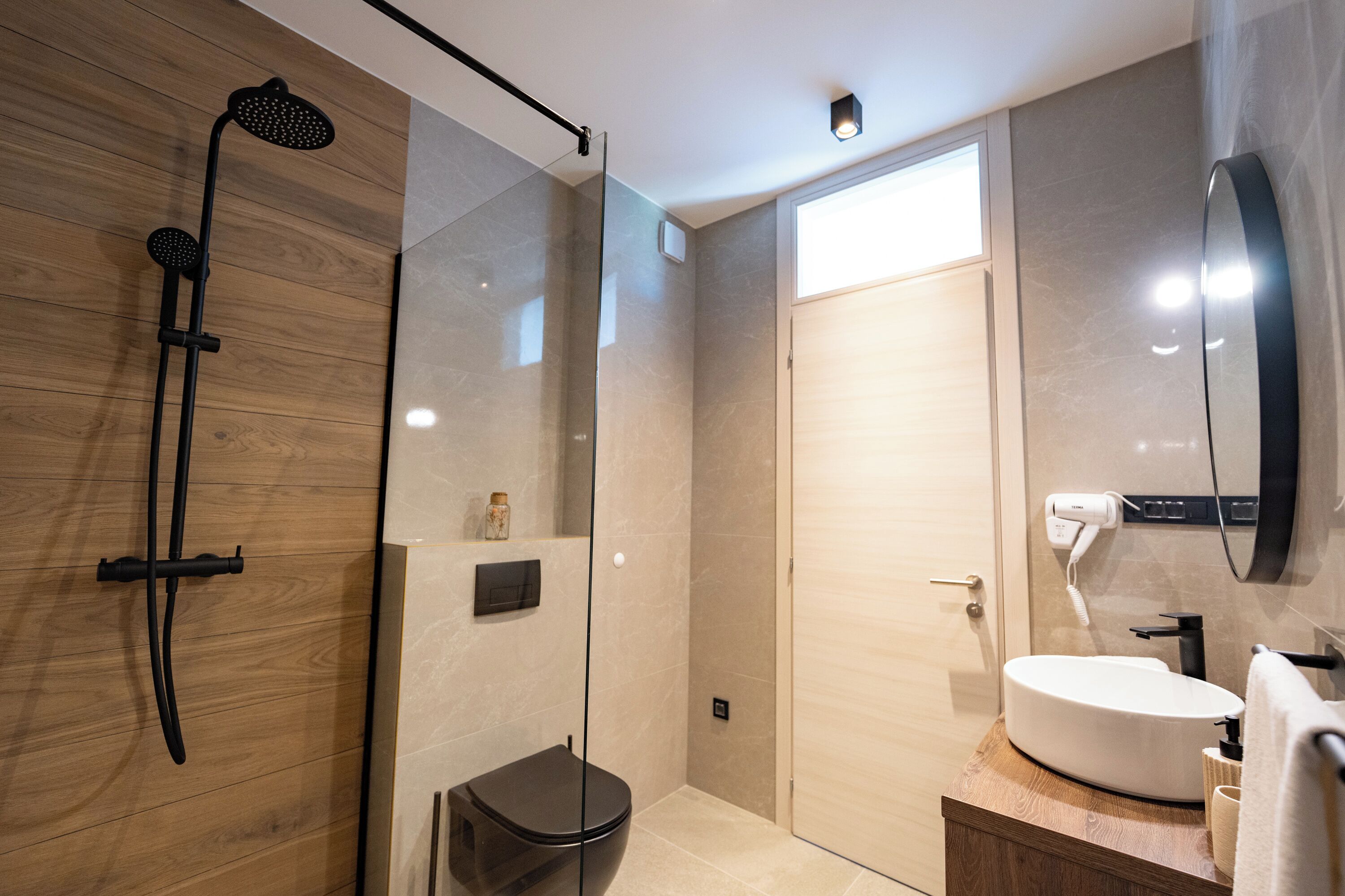 Une salle de bain moderne avec une douche à parois de verre, un meuble-lavabo en bois et un miroir.