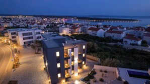 Un edificio moderno de varios pisos, un estacionamiento y vistas al mar.