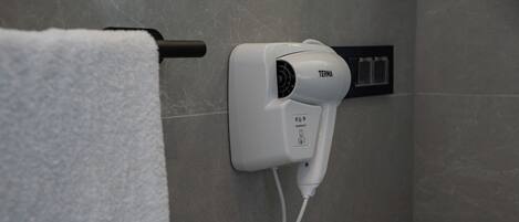 Een haardroger bevestigd aan een muur in een badkamer.