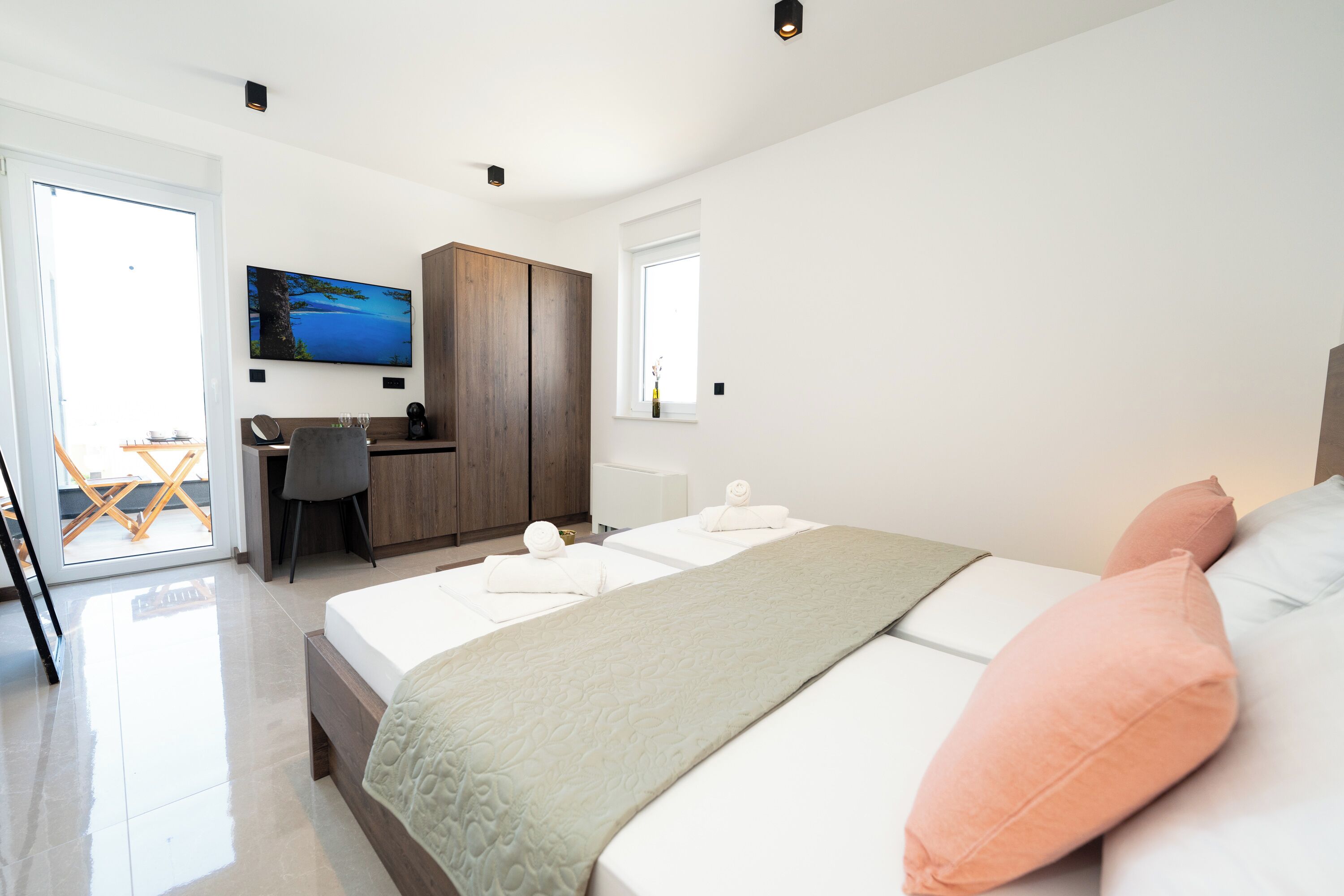 A modern hotel room with a large bed, a desk, and a television.