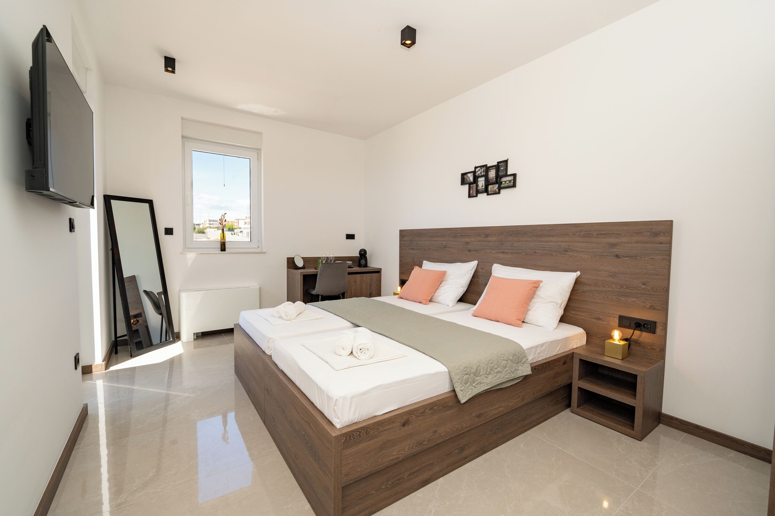 A modern bedroom with a large bed, bedside tables, a desk, and a TV.