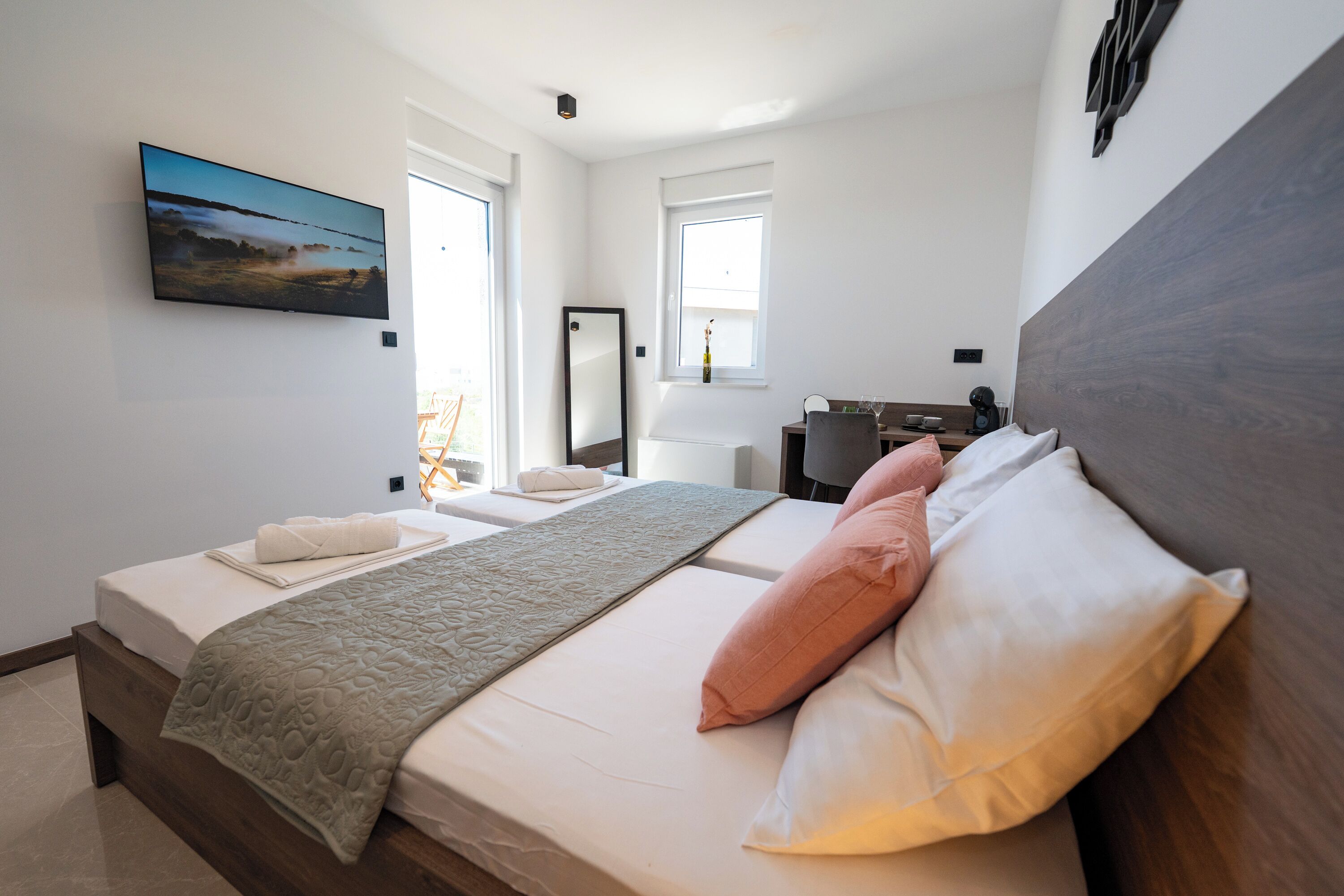 Une chambre moderne avec un grand lit, un téléviseur à écran plat, un miroir et une fenêtre.