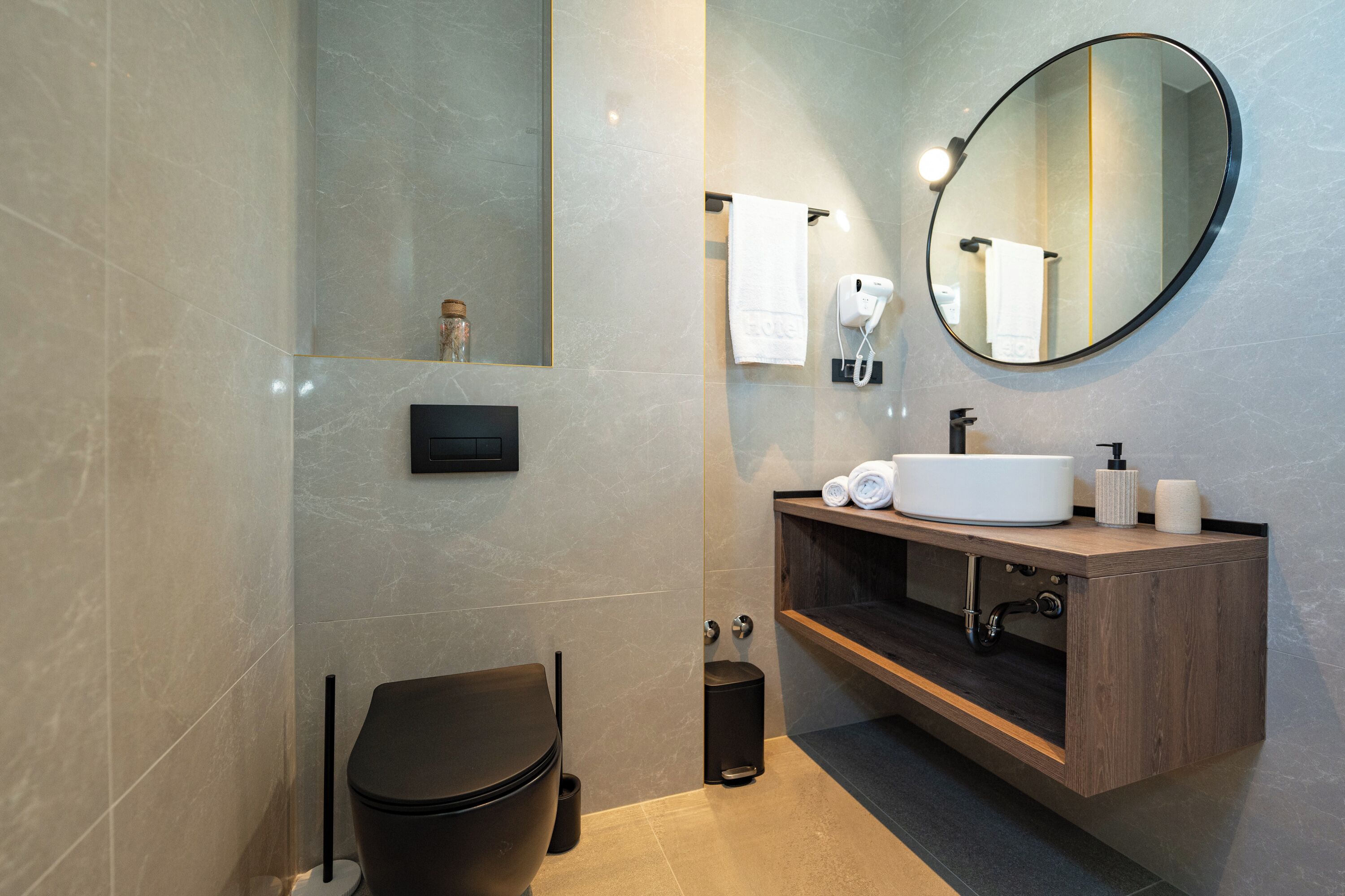 A modern bathroom with a toilet, sink, mirror, and towel rack.