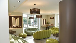 A modern interior with unique green seating, a visible 'Rivella' sign, and large windows. - The Originals Boutique Hotel Rivella (Clisson)