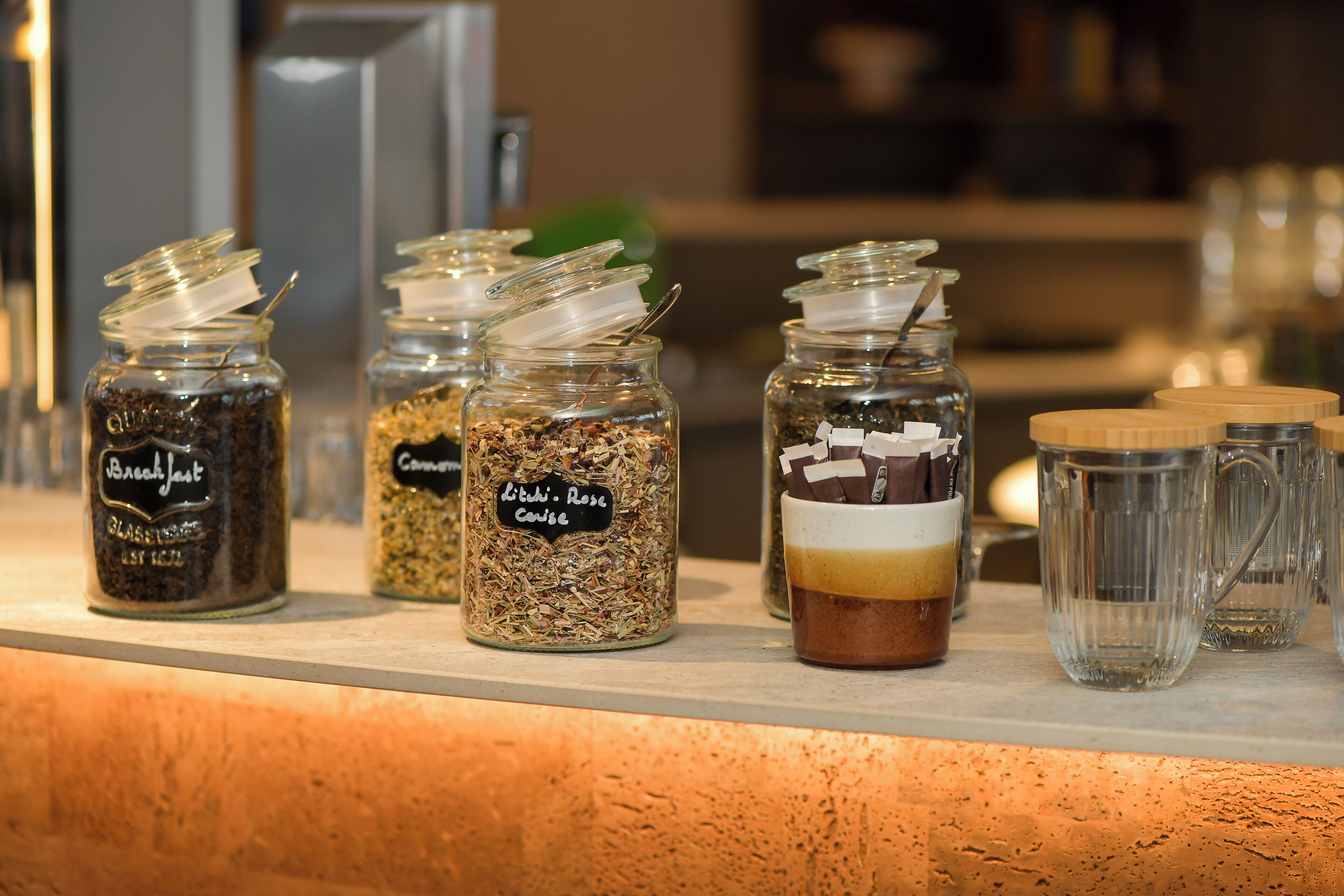 A display of various food items and beverages, including jars labeled with names and ingredients, and a mug with a layered drink.