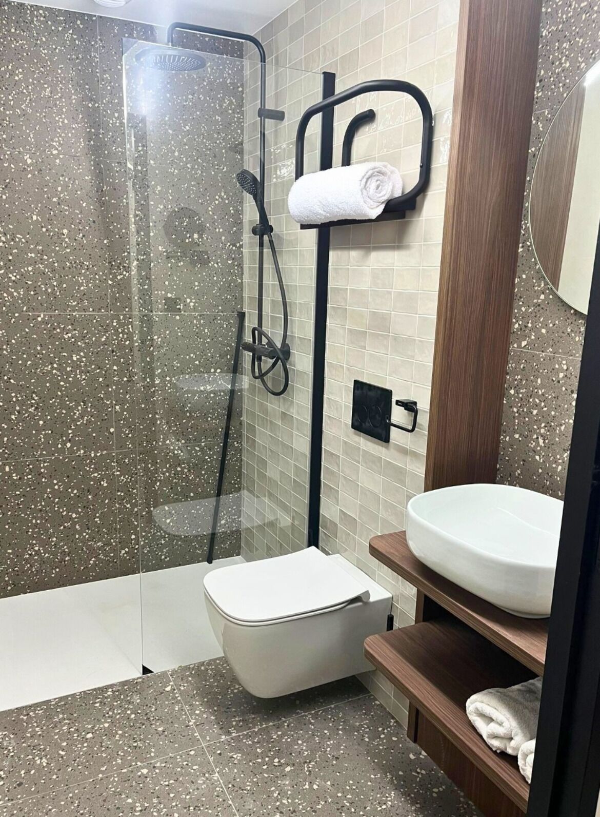 A modern bathroom with a glass-enclosed shower, a white toilet, and a wooden vanity with a sink.