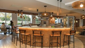 A modern bar area with a central island, bar stools, and a variety of lighting fixtures. - The Originals Boutique Hotel Rivella (Clisson)
