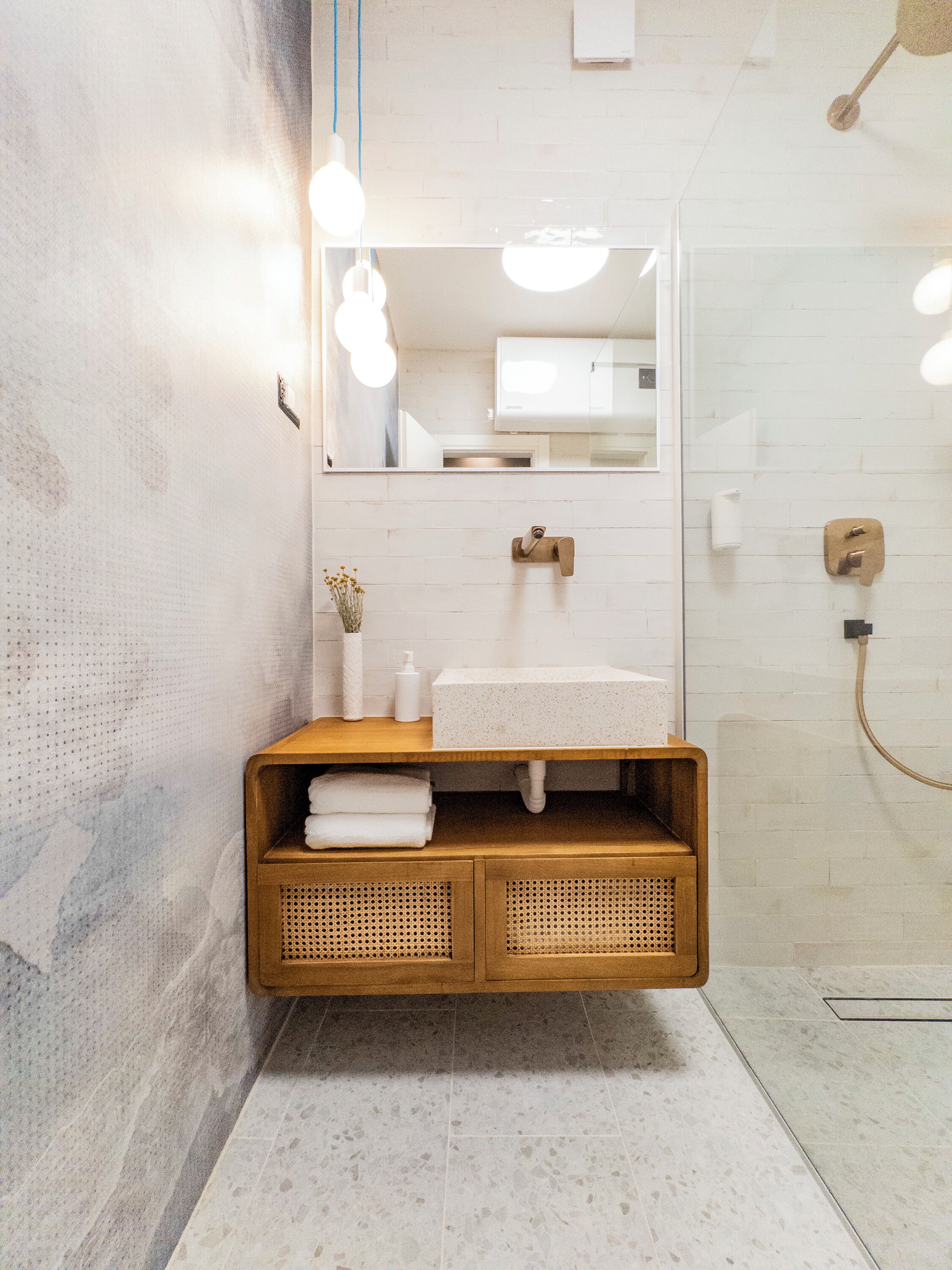 A modern bathroom with a wooden vanity, a large mirror, and a shower area.