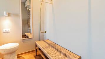 A modern bathroom with a wooden bench, a toilet, and a wall-mounted towel rack.
