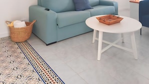 Una sala de estar moderna con un sofá azul claro, una mesa de centro blanca y una alfombra estampada.