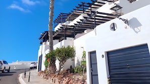 Un edificio moderno con fachada blanca, una palmera y una puerta de garaje negra.