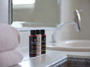 Casa de banho com lavatório e três frascos de gel de banho ZEALONE no balcão.