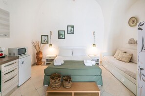 A room with a bed, a sofa, a small kitchenette, and a dining table. - Casetta Carlotta by Rentbeat (Ostuni)