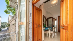 A corridor with wooden doors, a dining area with a table and chairs, and a view of the street outside.