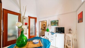 A compact living space with a dining area, a television, and a small table with a decorative vase.