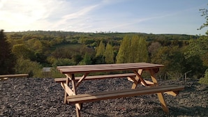 A picnic table with a view of rolling hills and trees in the background. - Llandovery - Cabin - Sleeps 2 - Parking - Garden (Llandovery)
