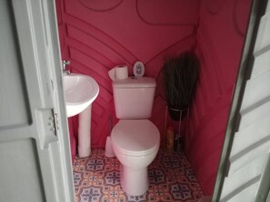 A small bathroom with a pink toilet, a white sink, and a broom. - Llandovery - Cabin - Sleeps 2 - Parking - Garden (Llandovery)