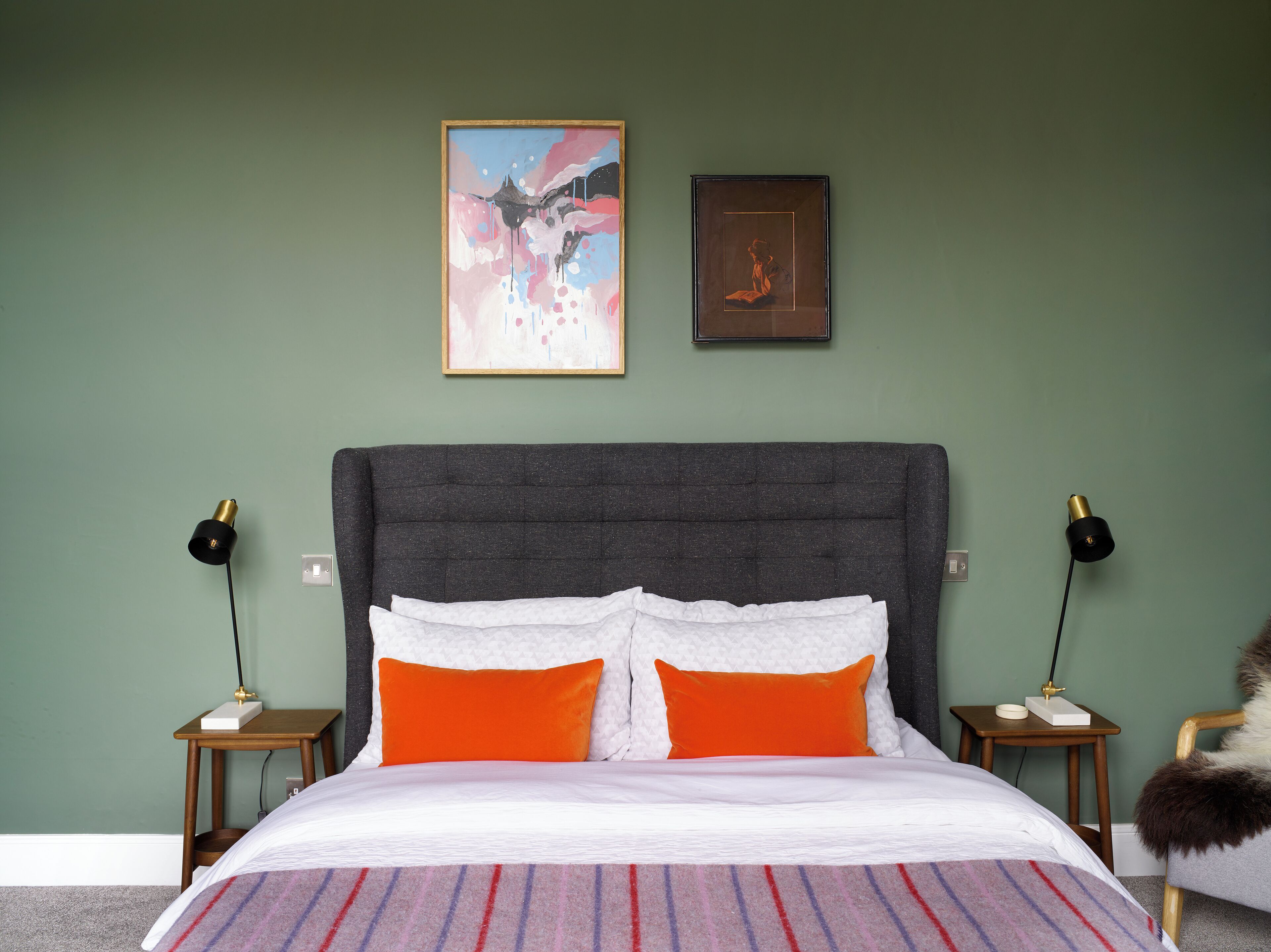 Quarto com uma cama grande, duas mesas de cabeceira, duas luminárias e duas imagens emolduradas na parede.