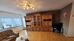 Een woonkamer met een houten vloer, een bank, een bijzettafeltje en een kast met glazen deuren.