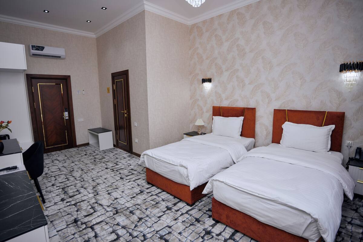 Habitación de hotel con dos camas, un escritorio y una silla.