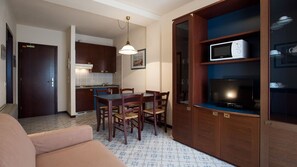 A compact living space with a kitchenette, dining area, and a television.