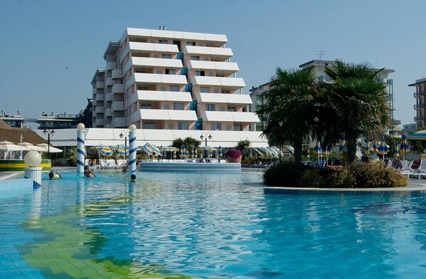 A hotel with a pool area, including a large pool and lounge chairs.
