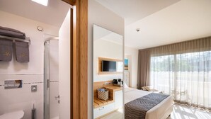 A hotel room with a shower, toilet, bed, and a view of the outdoors.