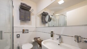 A modern bathroom with a glass shower enclosure, a white sink with a chrome faucet, and a toilet.