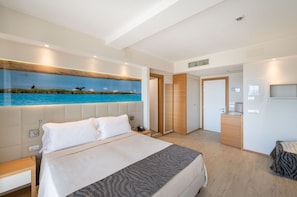 Un dormitorio moderno con una cama grande, un cuadro de una playa, un escritorio y un armario.
