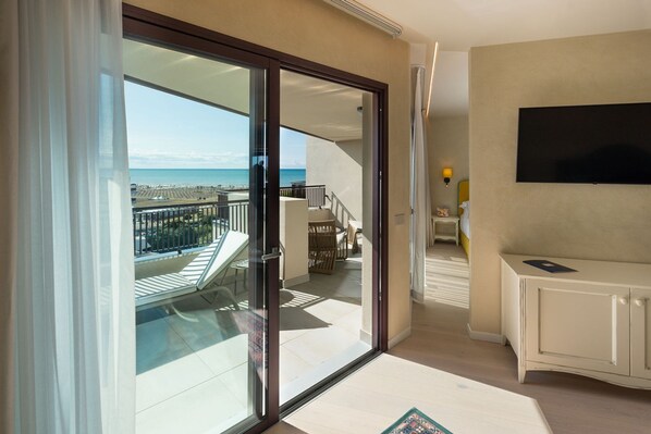 A hotel room with a balcony, a TV, and a staircase leading to another floor.