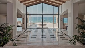A spacious lobby with a large glass wall offering a view of the ocean.