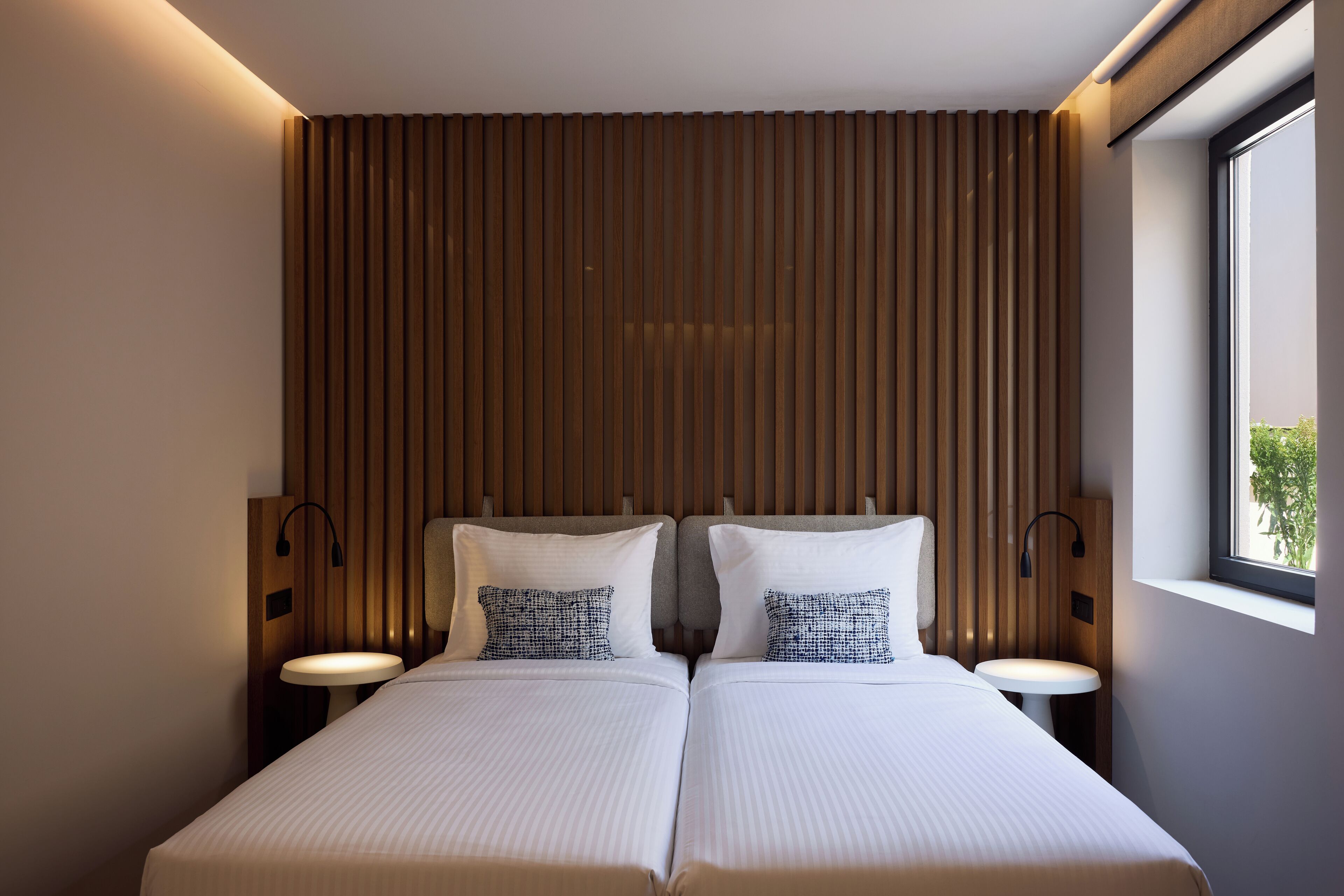 Una cama doble con dos mesitas de noche, cabecero de madera y ventana con vistas.