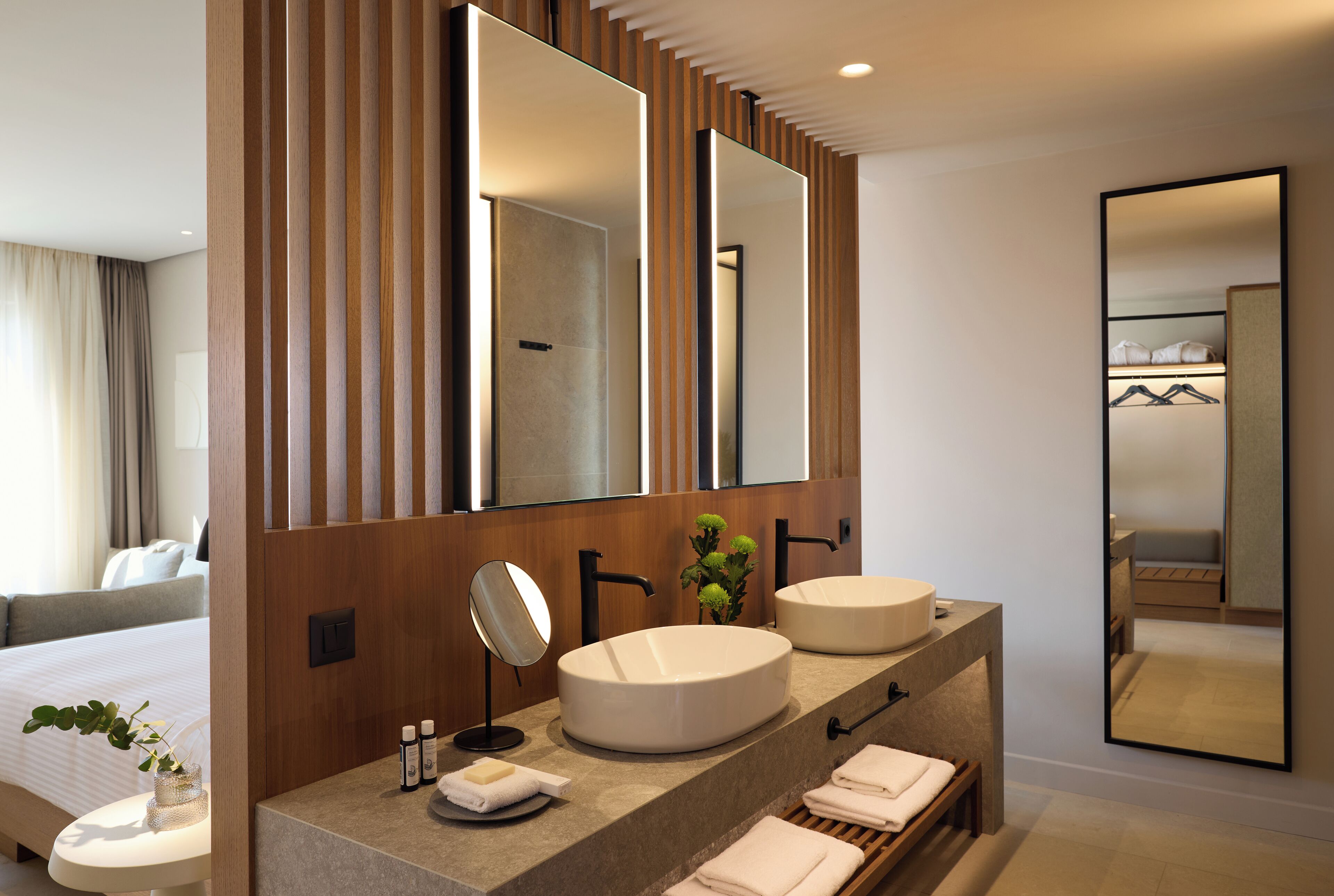 A modern bathroom with two sinks, a large mirror, and a wooden panel design.