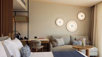 A modern hotel room with a bed, a sofa, a desk, and a small table.