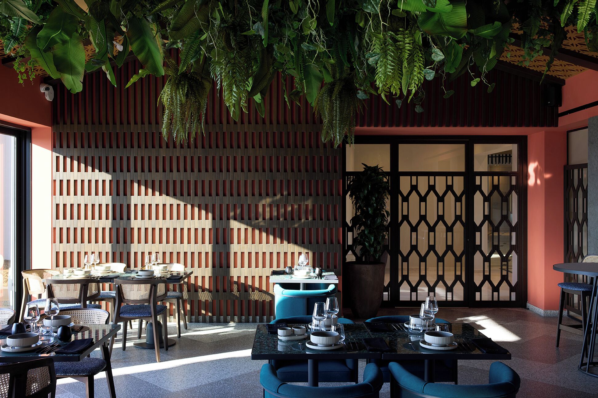 An outdoor dining area with tables and chairs, a wooden fence, and hanging plants.