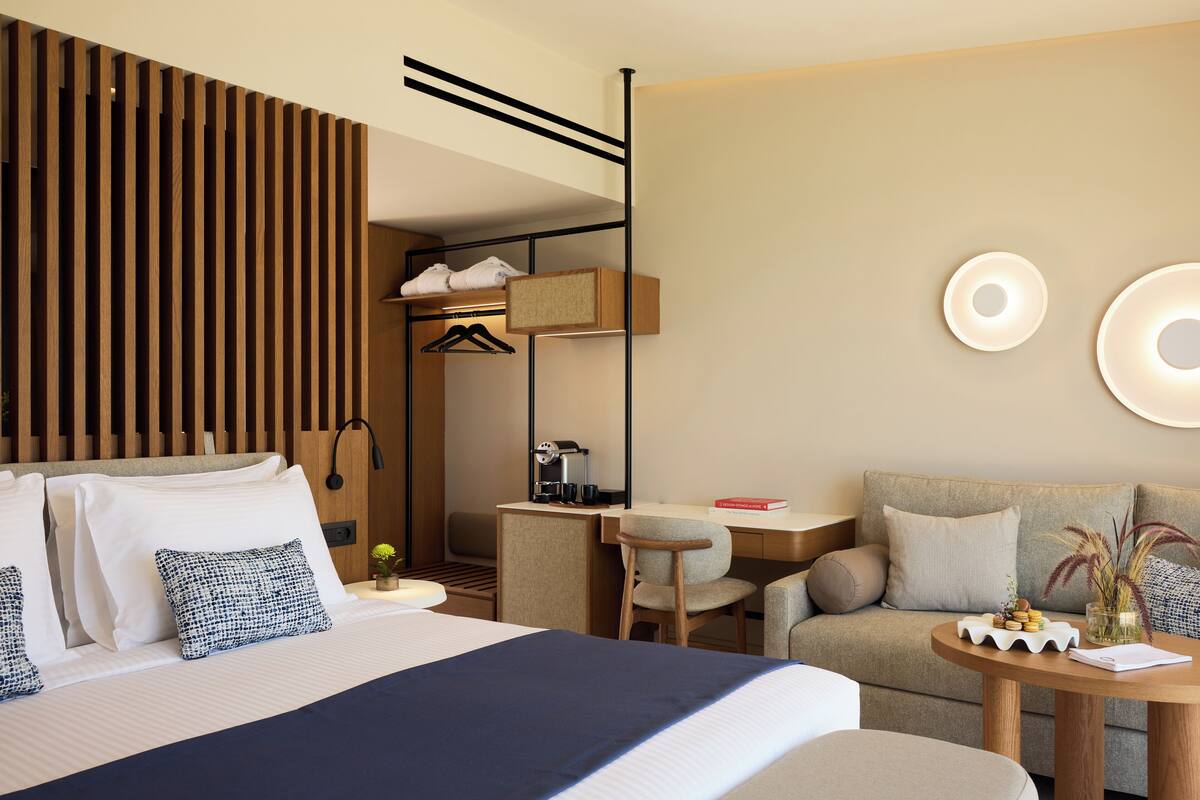 Ein Hotelzimmer mit Bett, Schreibtisch, Sofa und einem kleinen Tisch mit einer Vase.