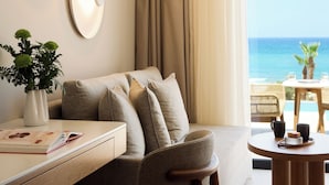 A modern hotel room with a sofa, a dining table, and a view of the ocean.
