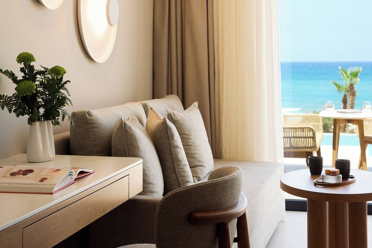 Ein modernes Hotelzimmer mit einer Couch, einem Esstisch und Blick auf den Ozean.