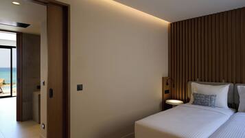 Una habitación de hotel moderna con una cama grande, un panel de pared de madera, una mesita de noche y vistas a la playa.