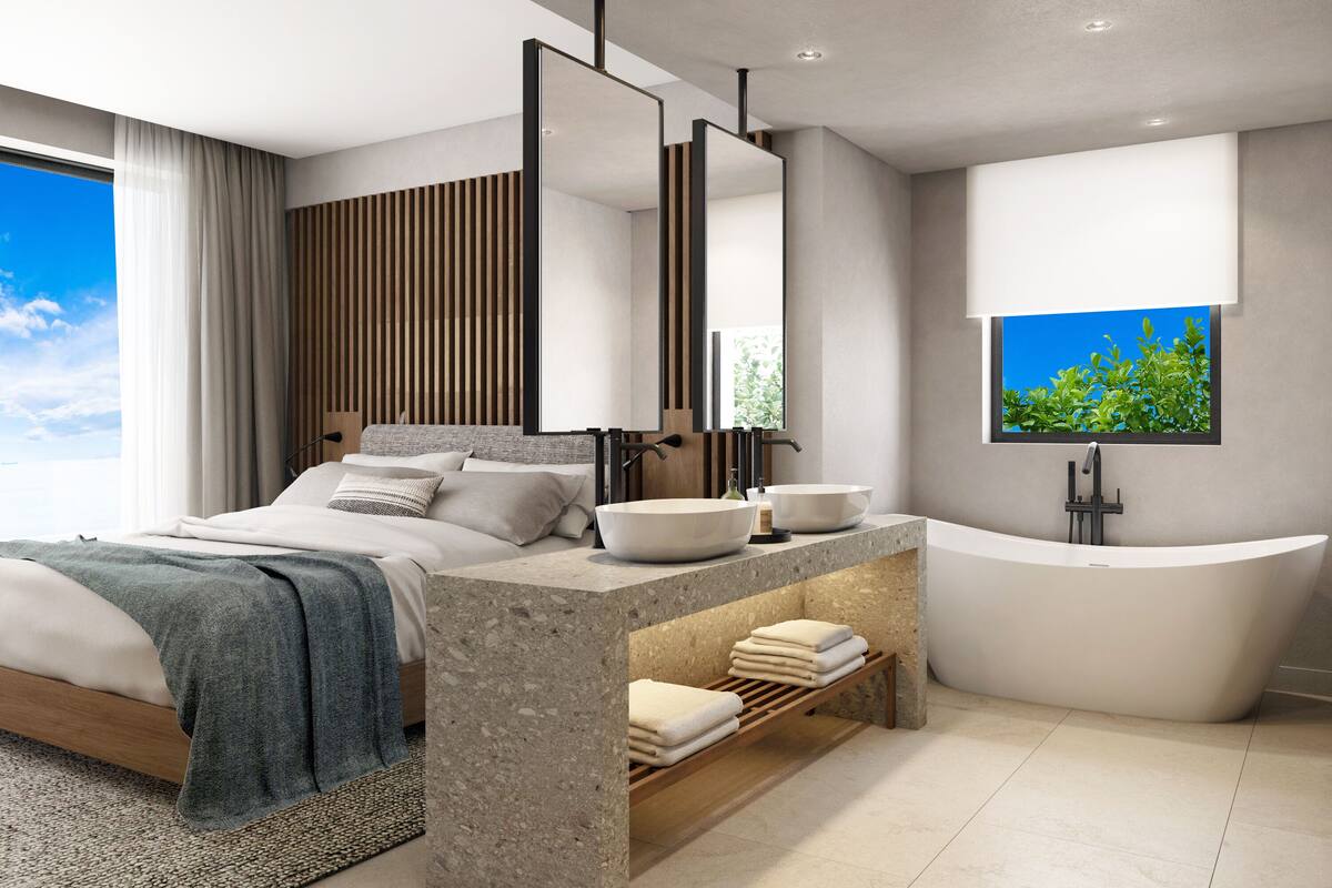 Ein modernes Schlafzimmer mit einem großen Bett, einem Schminktisch mit freistehender Badewanne und einem großen Fenster mit Blick auf Grünflächen.