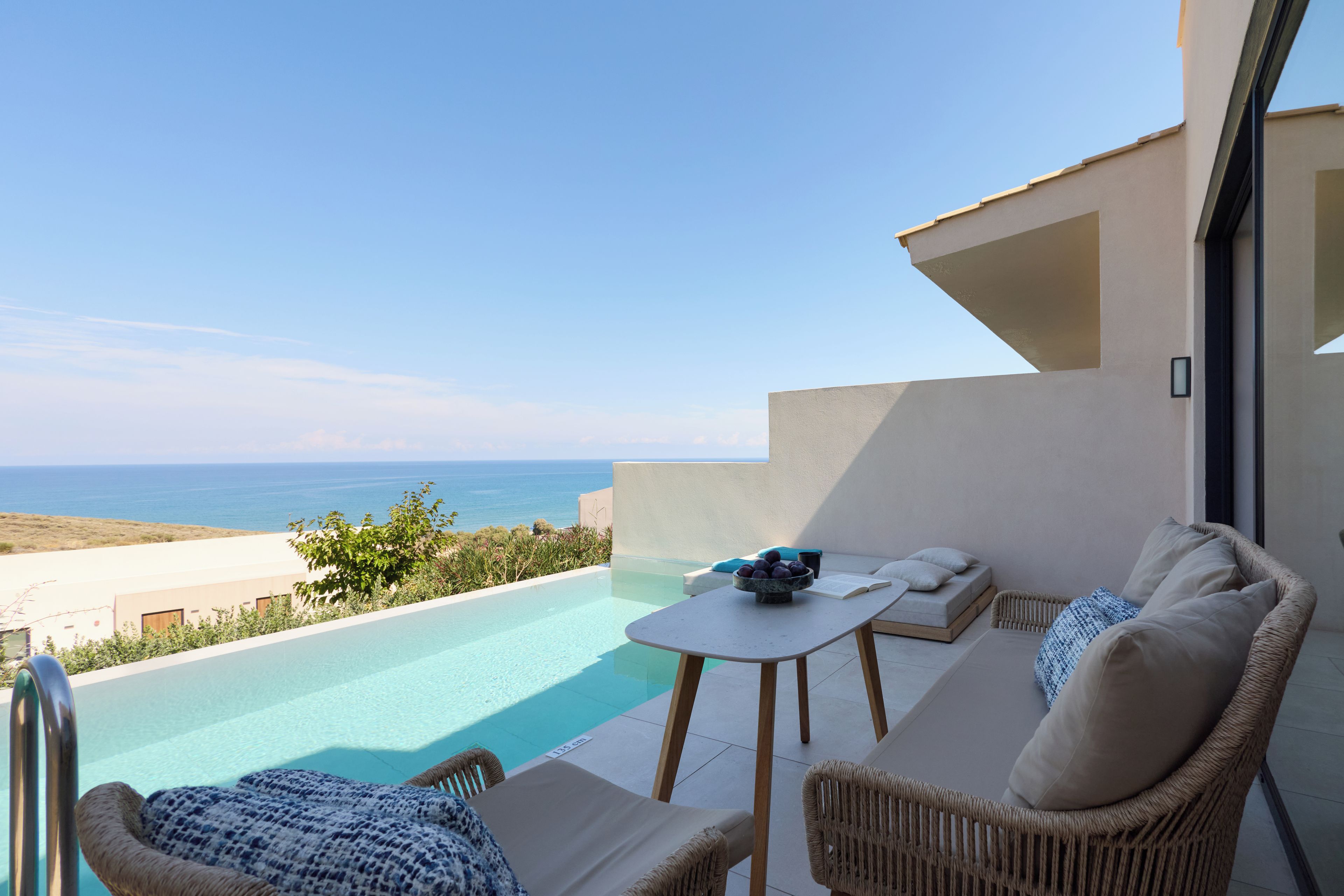Un balcón con vistas al mar, una piscina y mobiliario exterior.