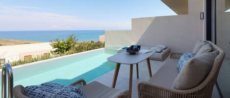 Un balcón con vistas al mar, una piscina y mobiliario exterior.