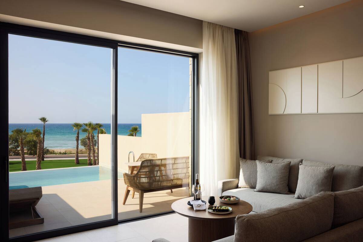 Ein modernes Hotelzimmer mit einer großen Schiebetür zu einem Balkon mit Pool und Meerblick.