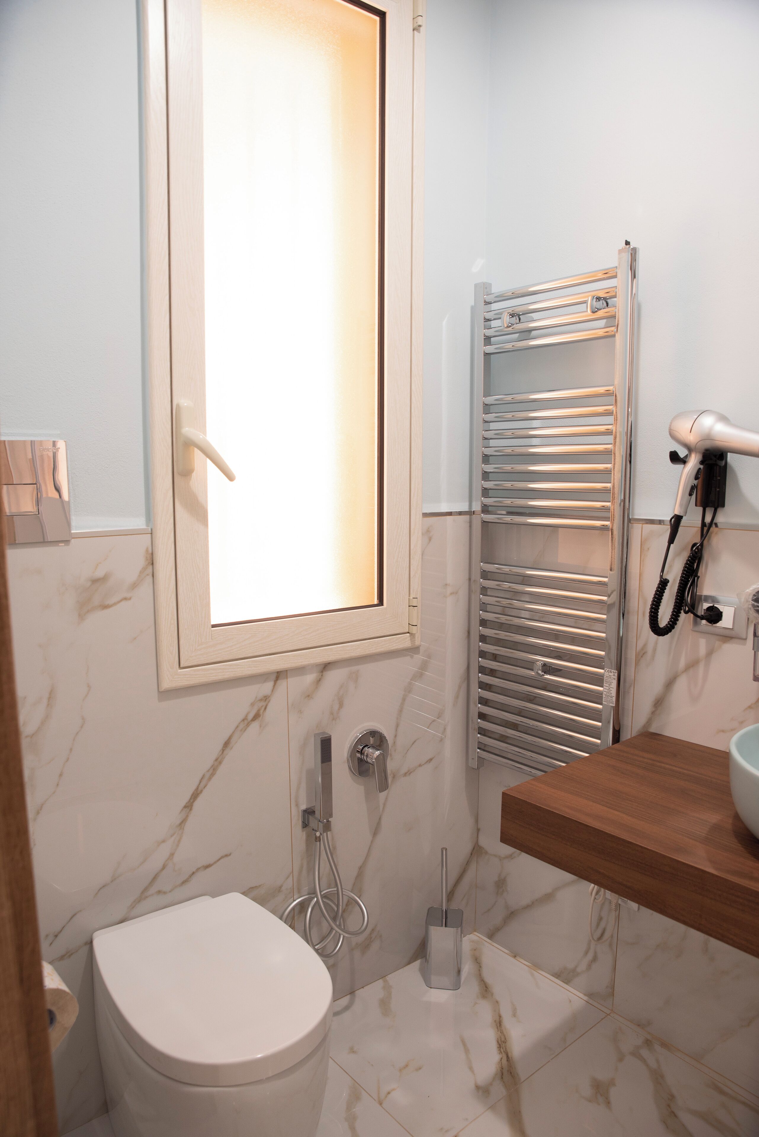 Un baño moderno con inodoro, ducha, toallero y secador de pelo.
