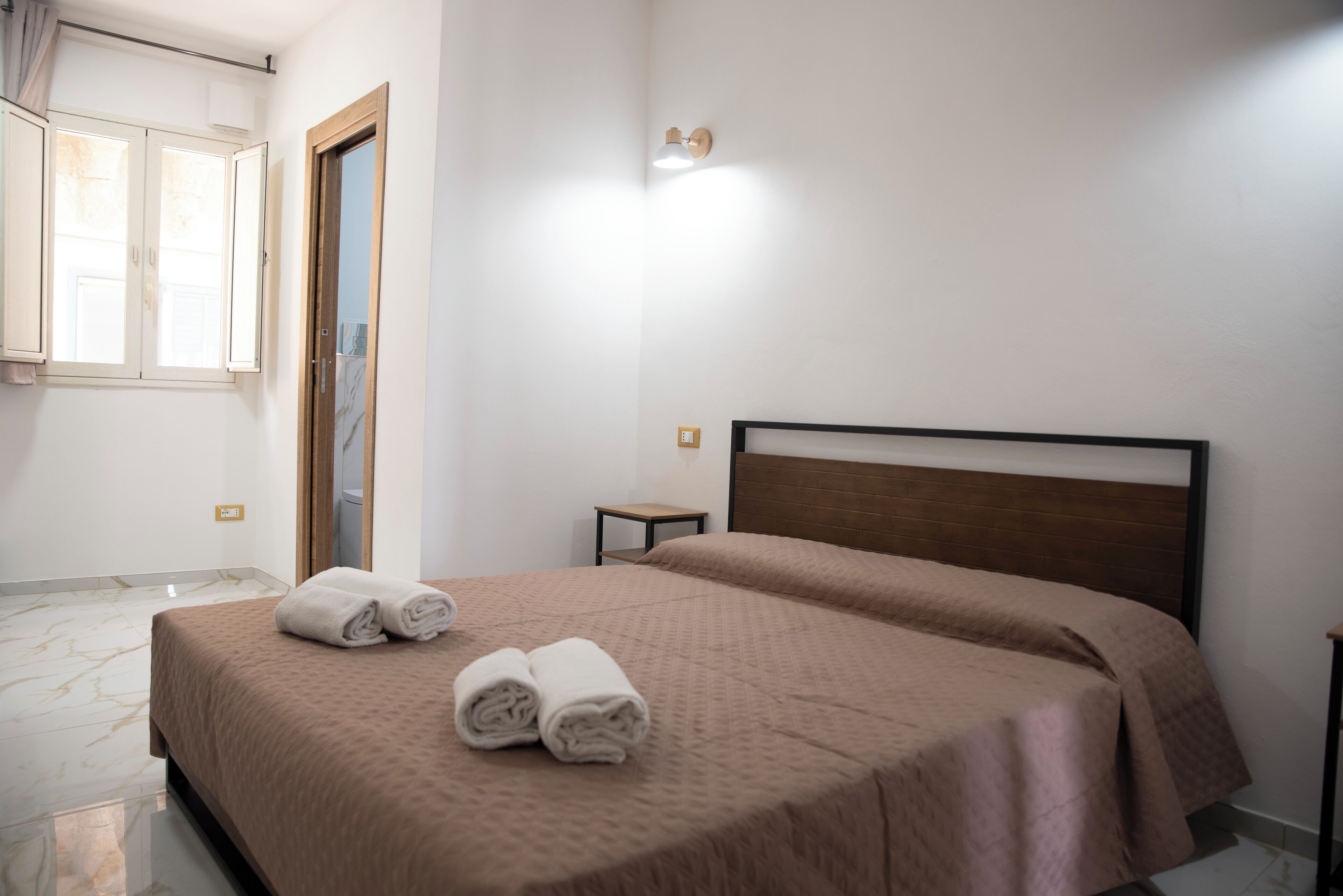 Una habitación de hotel con cama, una mesita y una ventana con cortinas.